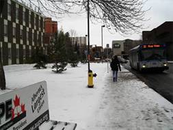 Person walking towards a bus along a snow covered footpath